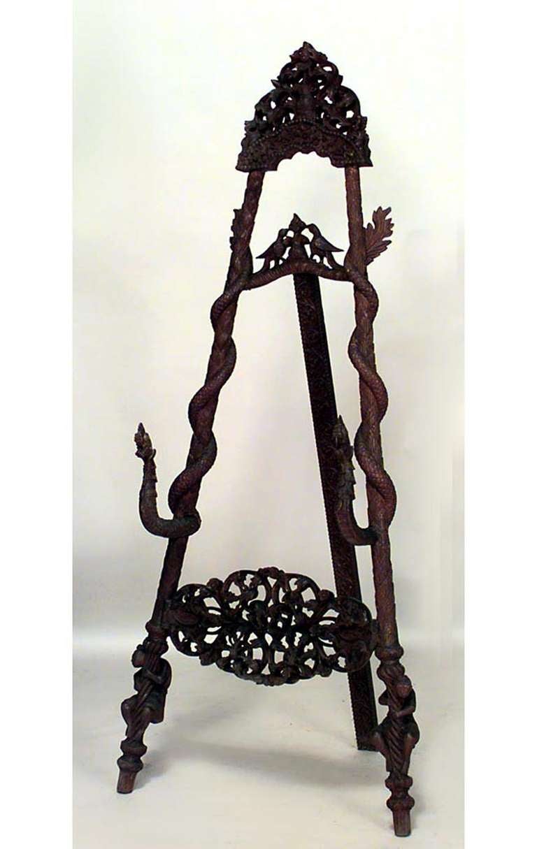 Nineteenth century Burmese style rosewood easel carved with a filigreed finial top and center panel as well as foliate and animal forms, such as birds, monkeys, and a pair of life-size snakes coiled around two of the piece's legs.