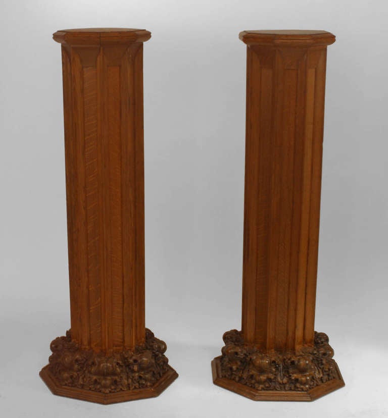 Pair of octagonal oak Gothic Revival pedestals with carved oak leaf design bases and trim carved in imitation of architectural molding.