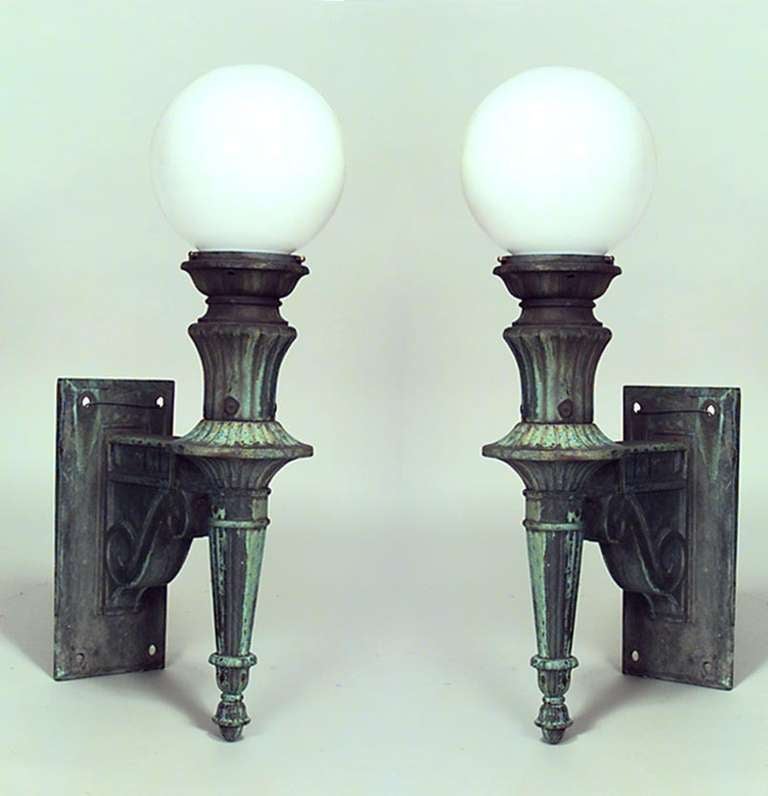 Pair of American Victorian green patinated bronze outdoor sconces with torch-form bases and spherical white glass tops.

Additional pair available. Priced per pair.