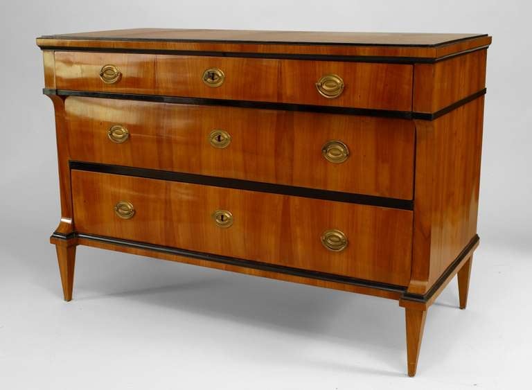 Austrian Biedermeier cherrywood chest accented with ebonized trim and oval brass handles with three stepped drawers and four tapered square legs.