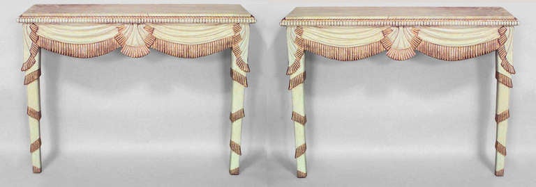 Pair of French Art Deco cream painted and gilt trimmed bracket console tables with carved swag and fringe designs.