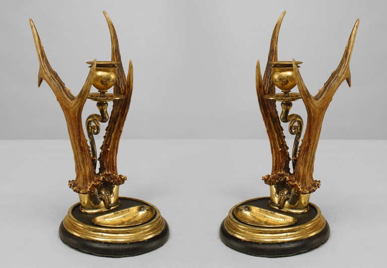 Pair of Continental brass candlesticks with a single candlestick stem centered by two antlers on round brass base.