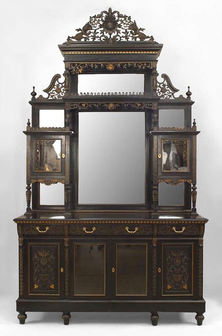 English Aesthetic Movement (19th Century) ebonized cupboard cabinet with gold incised and floral carved trim and mirrored back panels on upper section with filigree pediment top.

