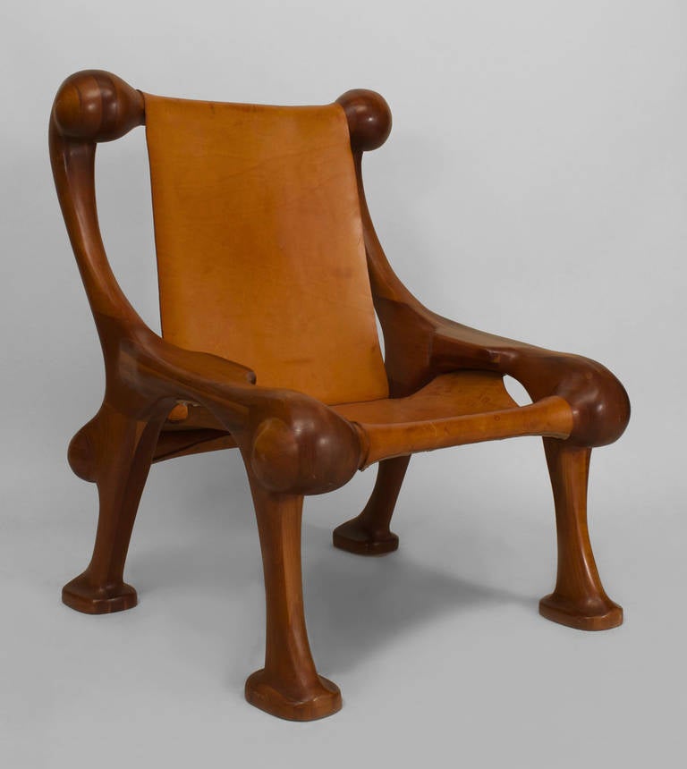 Signed and dated by American designer Martin Stan Buchner in 1977, this oversized lounge or arm chair features a leather saddle seat and back supported by a curved, stylized frame composed of laminated cherry wood