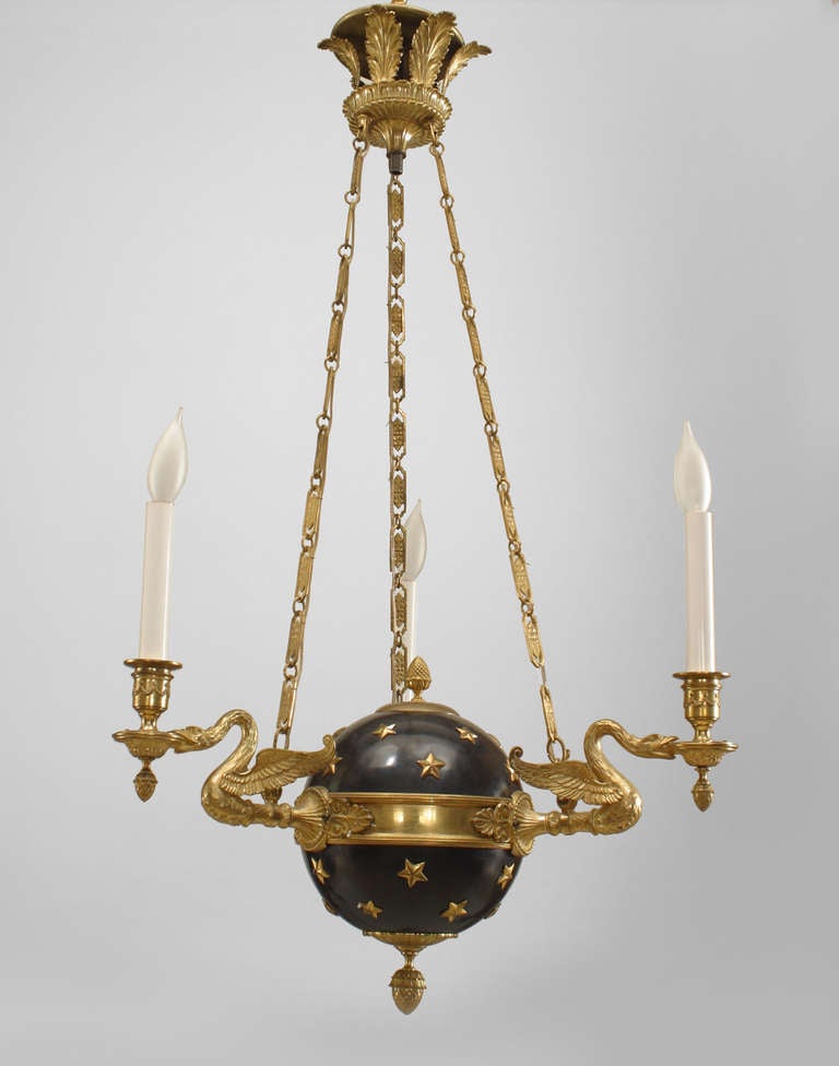 French Empire style ebonized globe form chandelier with applied gilt stars and an acorn finial bottom. The chandelier features three swan form arms and is suspended from a crowning feather bracket by three chains.