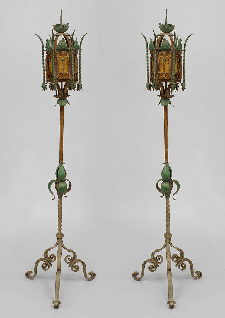 Pair of turn of the century Venetian wrought iron painted and decorated floor lamps. Each hexagonal, lantern-topped floor lamp features a finial top and six parchment panel shades and rests upon a polychrome stand terminating in three scroll legs.