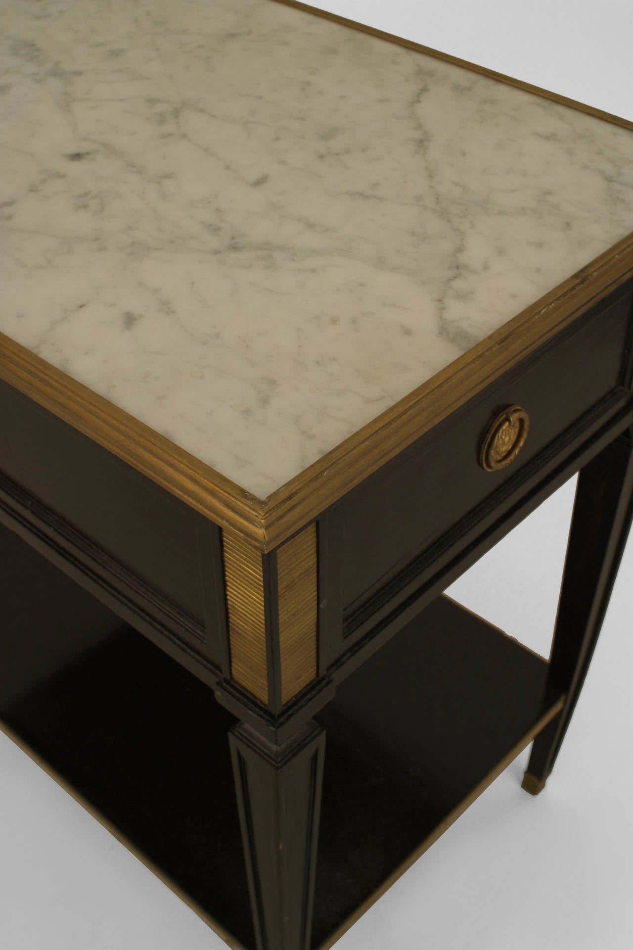 Pair of French 1940s (Louis XVI style) ebonized and bronze trimmed
rectangular end tables with small shelf stretcher and an inset white marble top above a drawer (stamped: JANSEN).