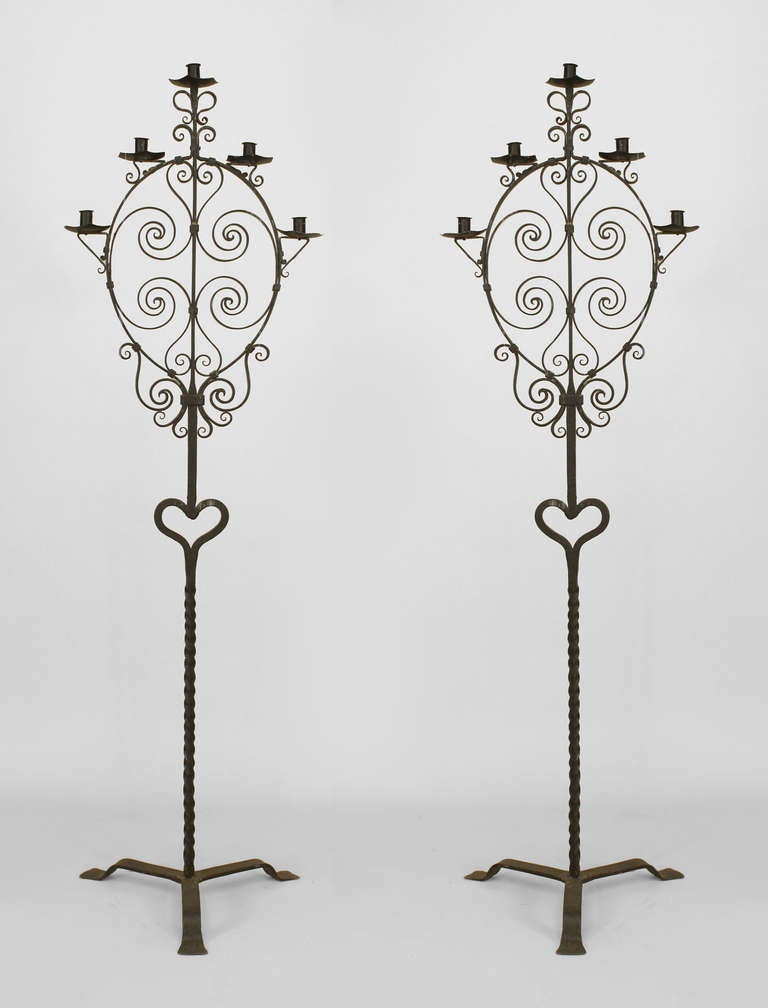 Pair of twentieth century Italian Renaissance style wrought iron floor torchieres resting upon tripod bases with five scroll design arms surrounding filigree centers.