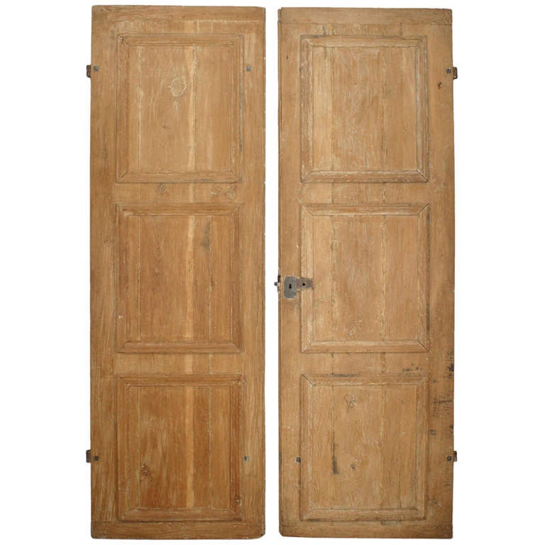 Pair of nineteenth century French Provincial stripped pine doors divided into three square panels and finished with iron hardware.