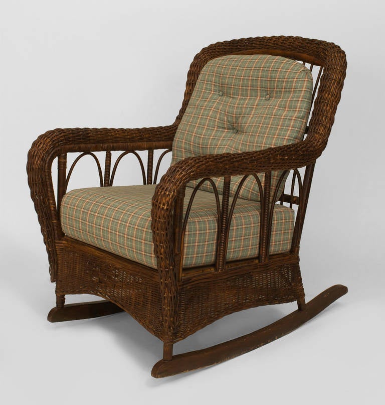 Attributed to American furniture makers Heywood-Wakefield, this early twentieth century Mission rocking chair is composed of brown stained and painted wicker with a woven frame and hoop design under arms with upholstered seat and back
