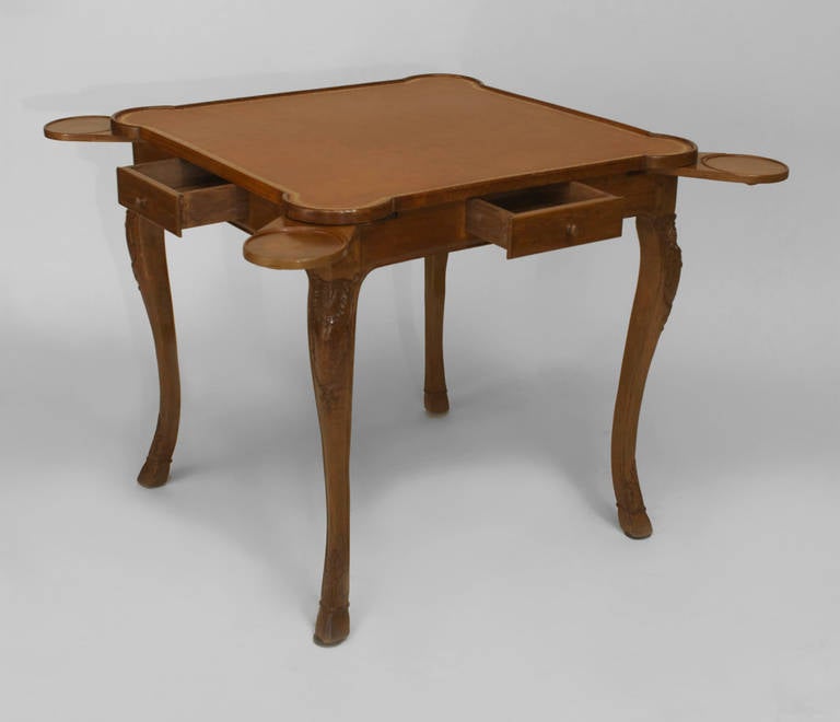 Twentieth century French Louis XV Provincial style carved walnut game table with a square top inset with gold-tooled brown leather and fitted with four centered drawers and pull-out side shelves above cabriole legs.