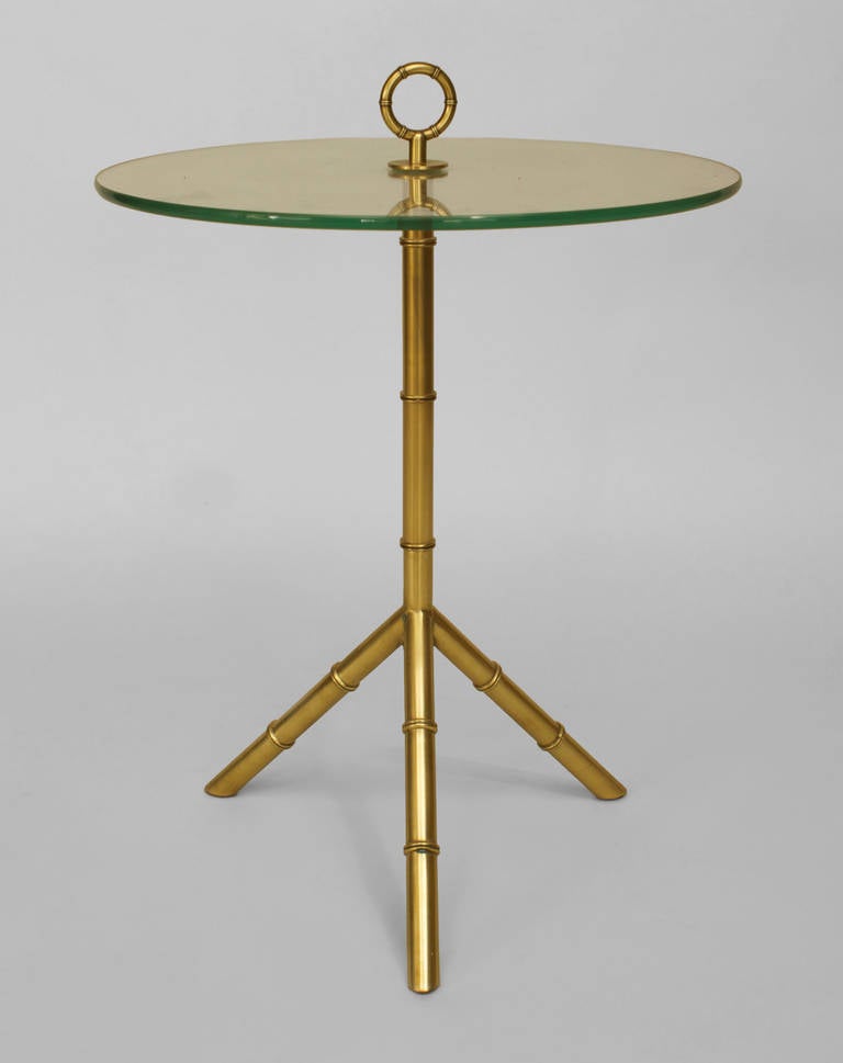 1960's French brass faux bamboo three leg end table supporting a round glass top with a centered ring finial.