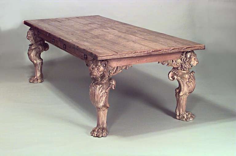 Large nineteenth century English dining table composed of stripped pine with a rectangular top over drawers and four lion carved clawfoot legs.