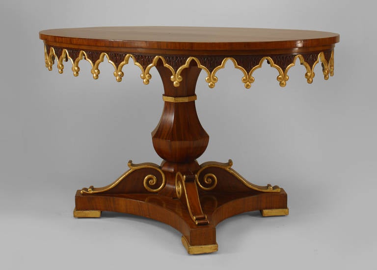 English Regency style (19th Century) oval mahogany and gilt trimmed pedestal base center table with Gothic design and scalloped apron.
