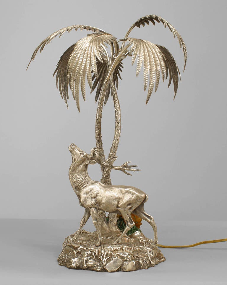 Pièce maîtresse victorienne de la fin du XIXe siècle composée de bronze argenté coulé en forme de cerf cornu regardant deux palmiers. La sculpture comporte des poinçons et a été montée ultérieurement avec une lampe et un abat-jour en verre à sa base.