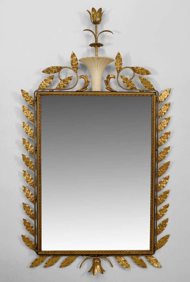 1940's gilt metal wall mirror attributed to French designer Gilbert Poillerat. The mirror is set within a gilt leaf and rope design frame crowned with a large alabaster urn issuing forth a tall tulip finial.
