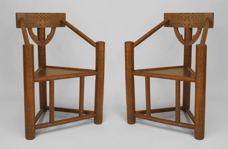 Paire de fauteuils en chêne de forme triangulaire, de style Oxford, du mouvement esthétique anglais, avec un motif sculpté sur le dossier.
 