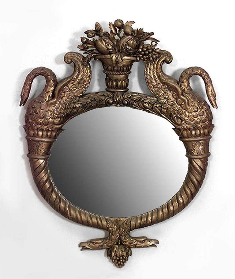 French Empire gilt oval horizontal wall mirror with swan-shaped sides and urn top with floral decoration.
