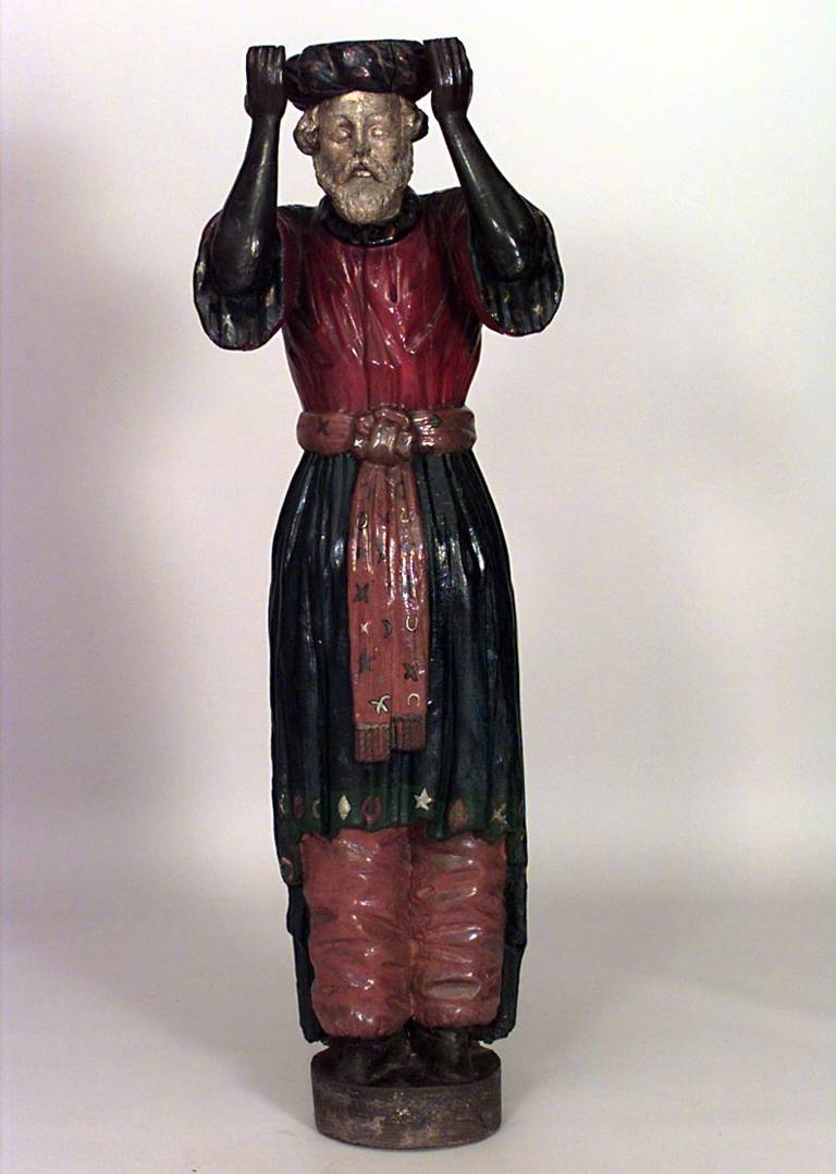 Nineteenth century carousel style carved and painted figure, possibly representing a Turkish male, wearing a head wrap and mystical robes with hands raised towards his face.