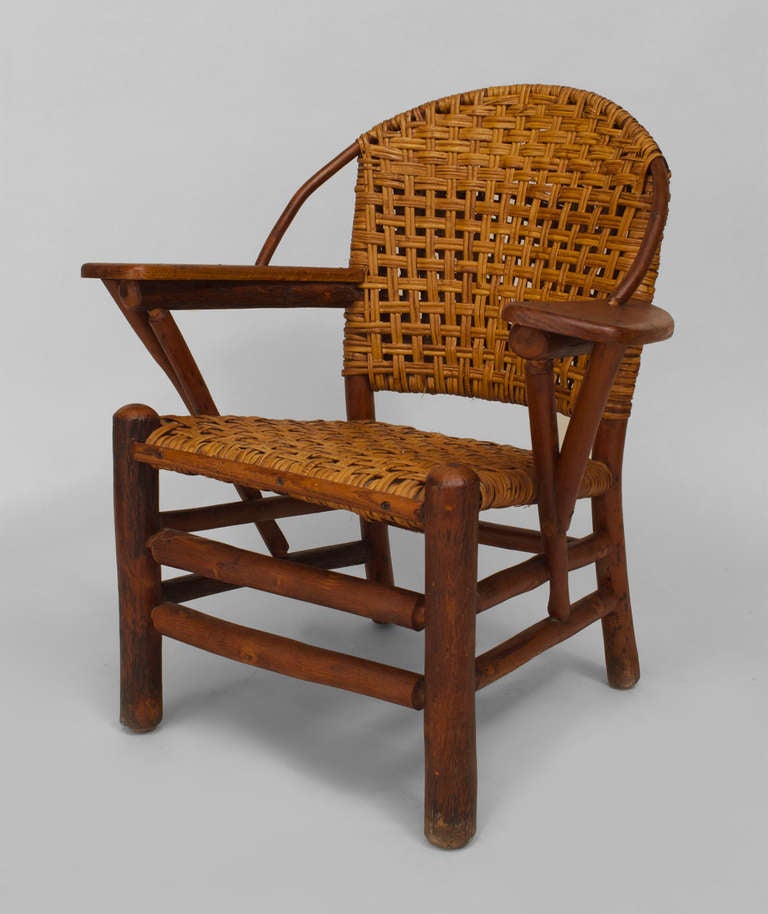 Bearing the brand of the Old Hickory Company of Martinsville, Indiana, this rustic armchair features a woven seat and round back with pine paddle form armrests above four round legs united by a double box stretcher.