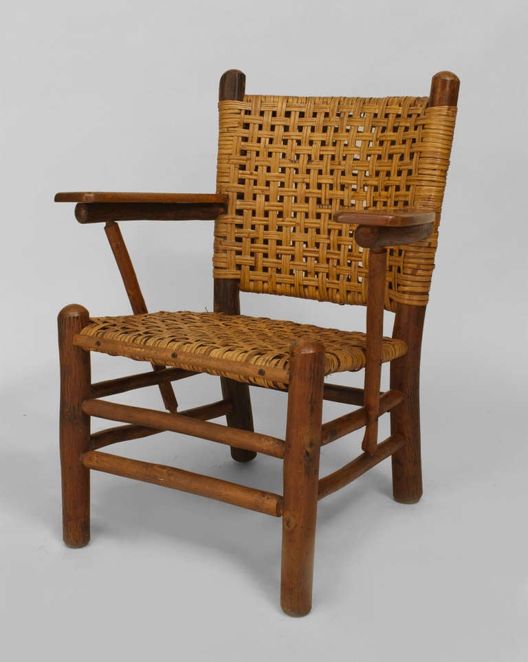 Bearing the brand of the Old Hickory Company of Martinsville, Indiana, this rustic armchair features a woven seat and square back with pine paddle form armrests above four round legs joined by a double box stretcher.