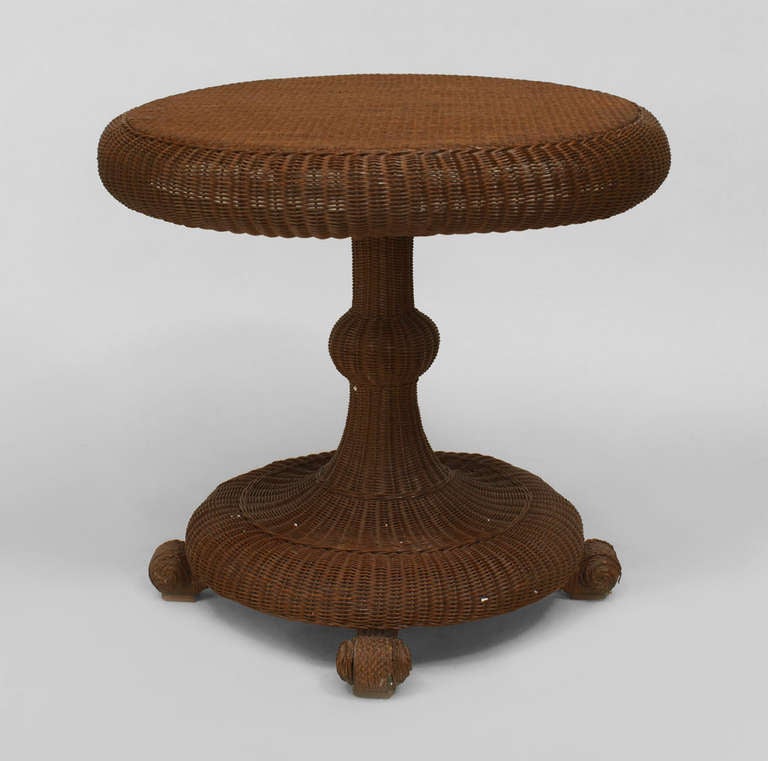 Attributed to noted American furniture makers Heywood-Wakefield, this nineteenth century end table is composed of woven natural wicker and features a circular tilt top supported by a sloped pedestal base with a circular bottom and bun feet that echo