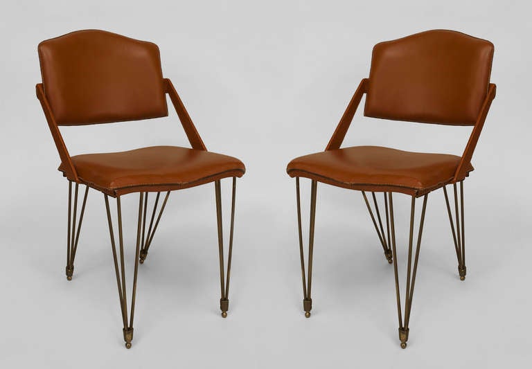 Pair of 1940s French open armchairs resting upon four tripartite metal spoke legs supporting a shaped seat and back joined by diagonal arms, all upholstered in light brown leather.