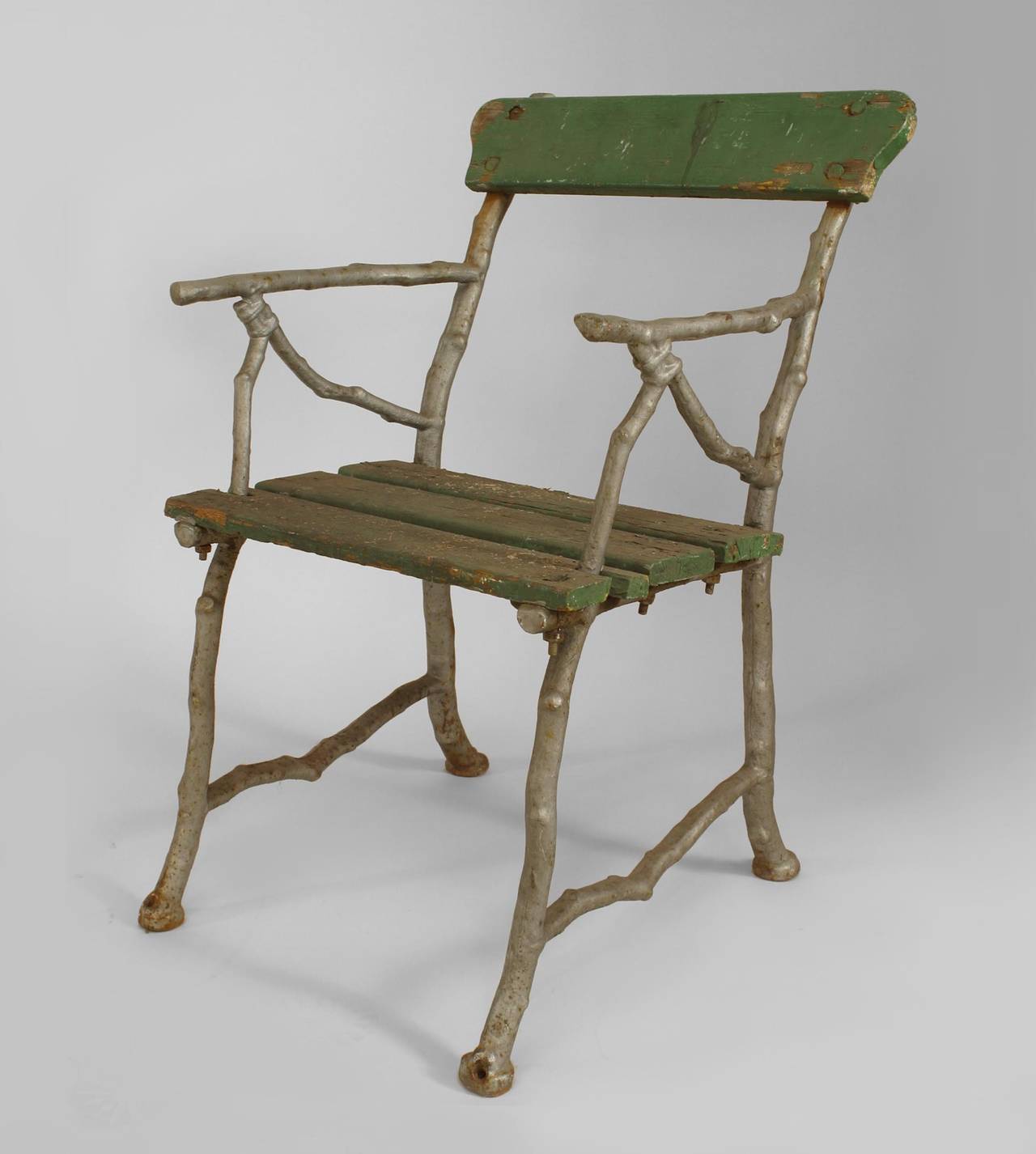 Outdoor English Victorian painted iron arm chair with faux twig design and painted slat seat and back.
