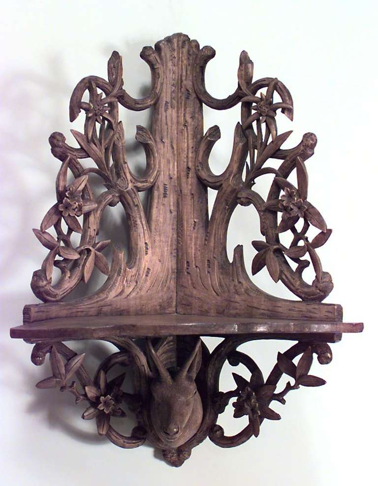 Nineteenth century German rustic corner shelf composed of stripped wood carved with arboreal and floral filigree designs around a central mounted deer's head carving.