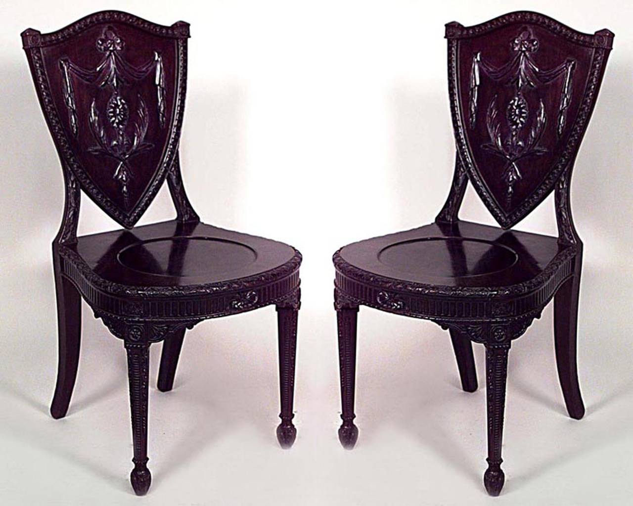 Pair of English Adam style (19th Cent) mahogany shield back (hall) side chairs with round carved seat.
