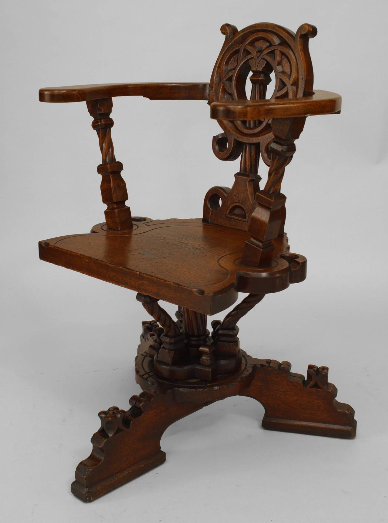German or English Arts and Crafts oak circle back swivel chair featuring elaborate, Medieval-inspired carved motifs and the brand 
