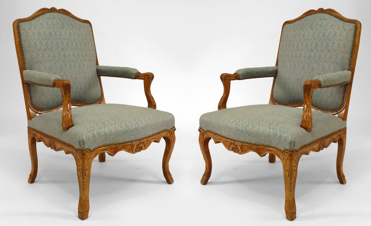 Pair of French Louis XV (18th Century) beech wood open Armchairs embellished with carved floral designs & shell motifs and upholstered seat, back, & arm rests
