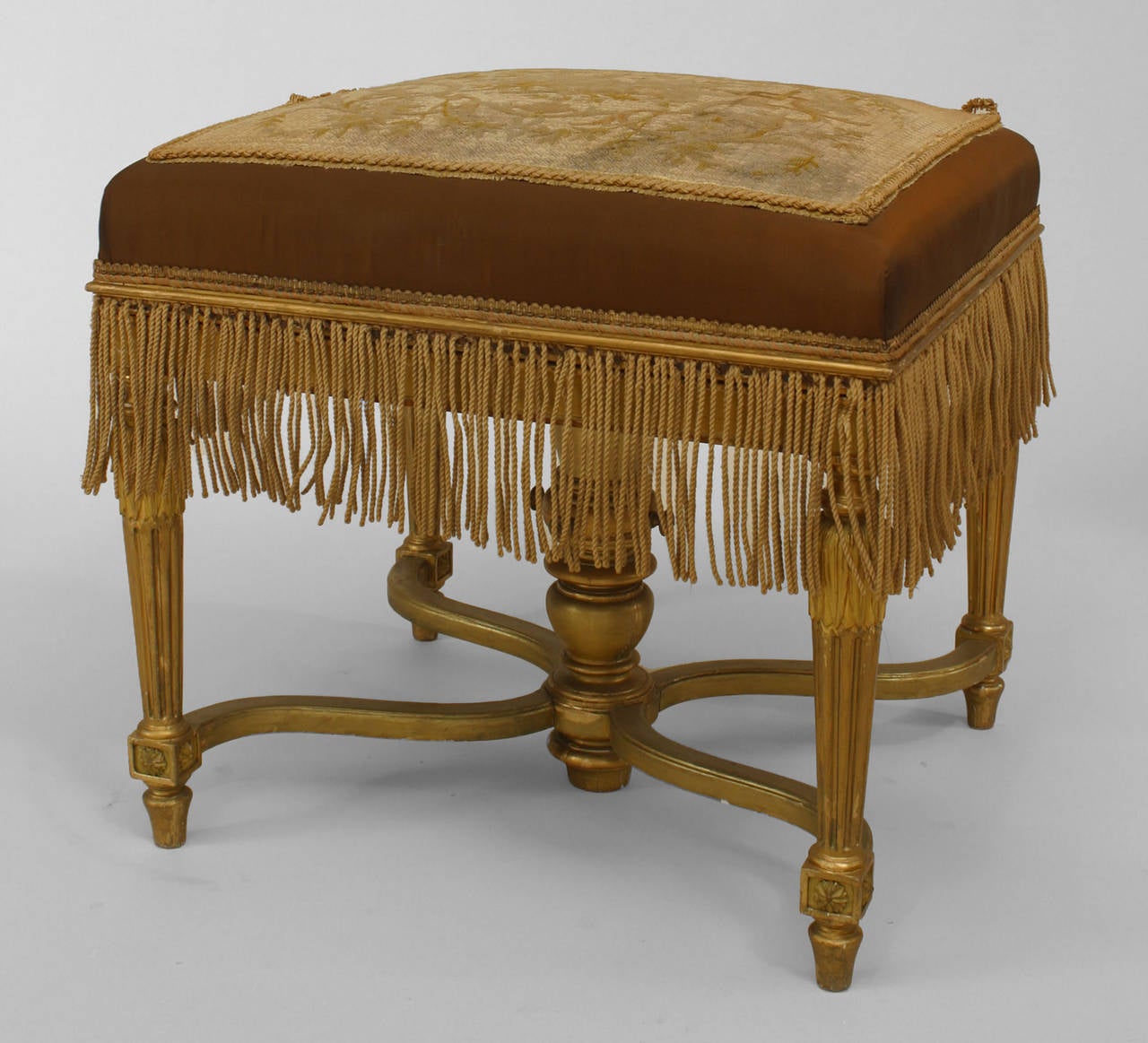 French Louis XVI style (19th Century) gilt bench with stretcher and embroidered seat with a fringe.
