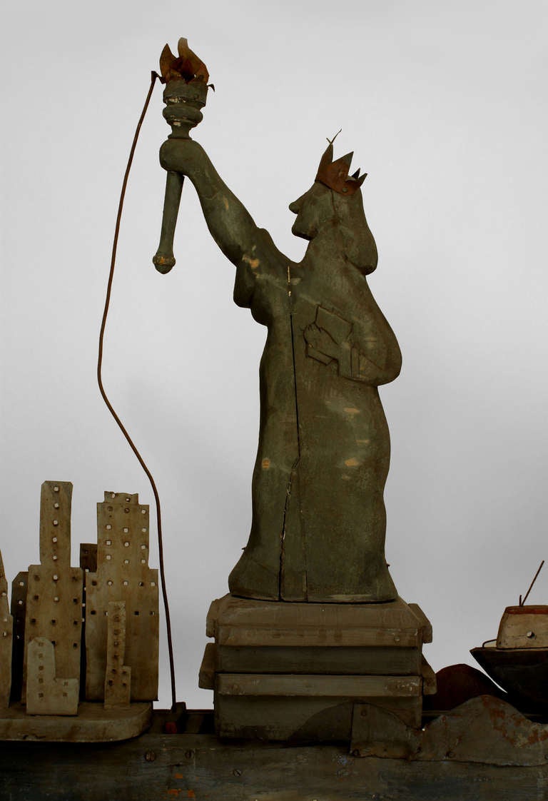 Twentieth century American carved and painted whirligig supported by a tall, thin metal base. The piece is decorated with Americana and immigration iconography, such as a cluster of skyscrapers, the Statue of Liberty, a steamship, and a billowing