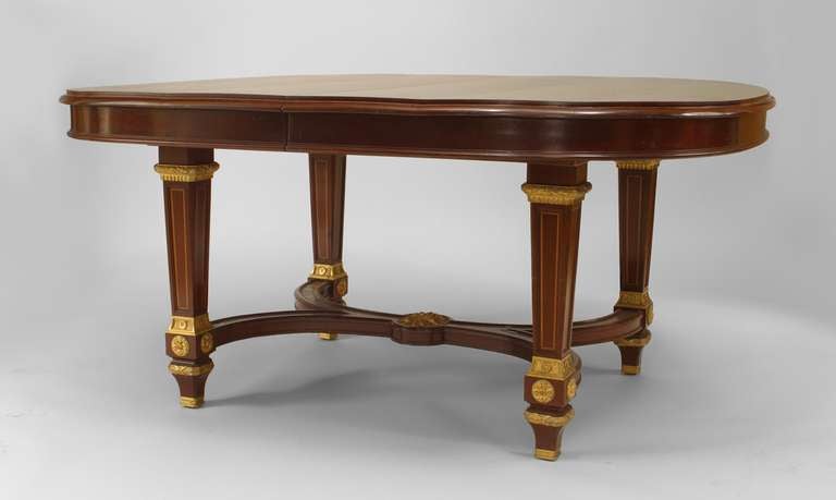 French Louis XVI-style (19th Century) mahogany oval dining table with bronze trim on a double scroll stretcher and legs with banded inlaid on legs (4 leaves at 19
