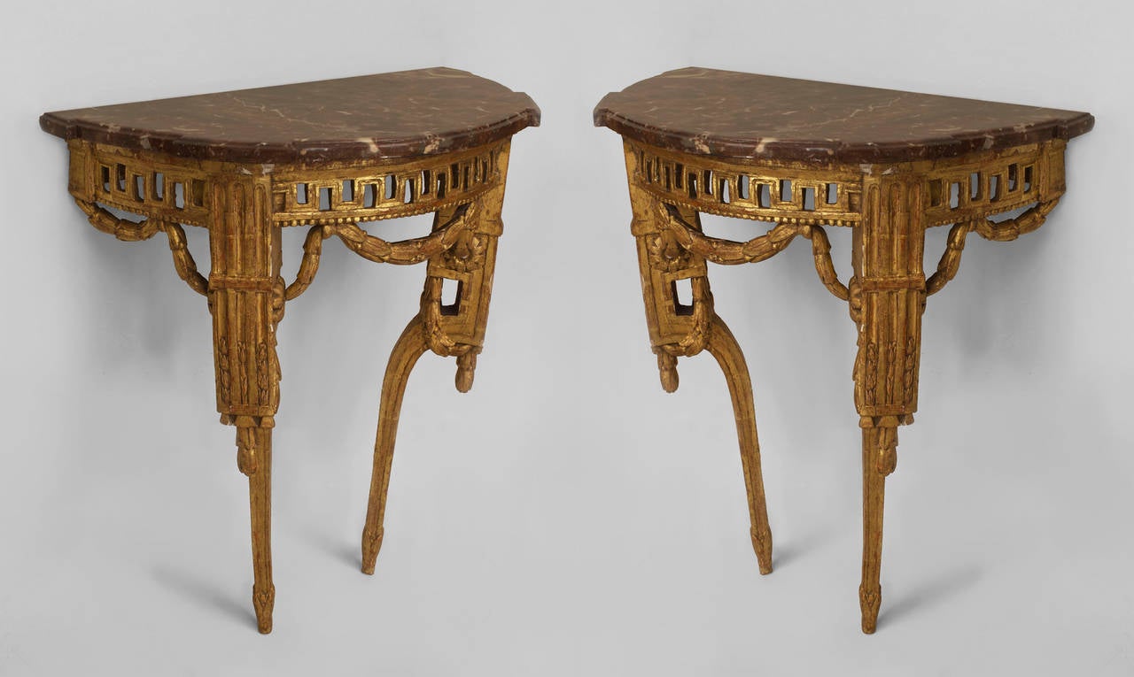 Pair of late 18th century Italian neoclassical marble and giltwood bracket console tables with shaped demilune rouge marble tops over filigree-carved and festoon frieze bases each supported by two fluted legs.