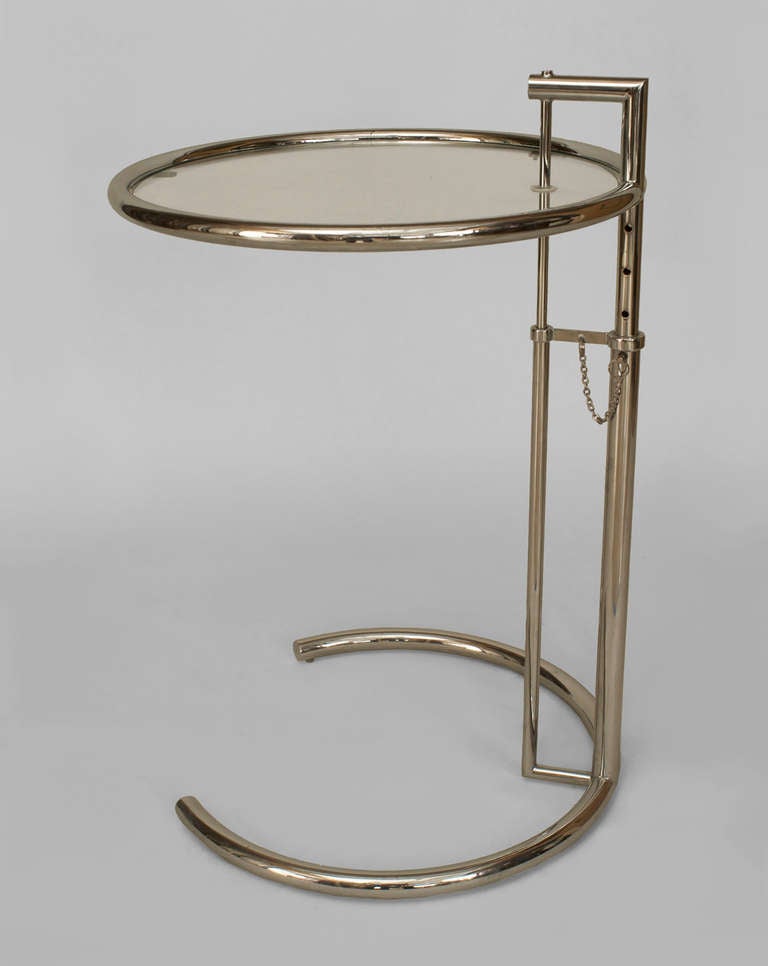 American Art Moderne style chrome end table with a round glass top attached to an incomplete circle base by two simple rods. The table's height is adjustable, ranging from 21 to 35 inches high.