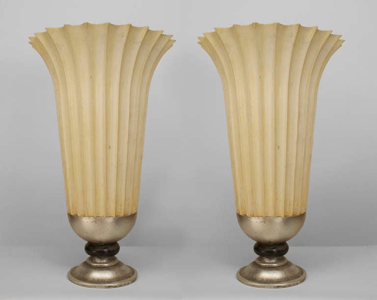 Pair of large mid-century American composition urns with flared and fluted cream-painted forms resting upon round silver bases with black-painted centers.