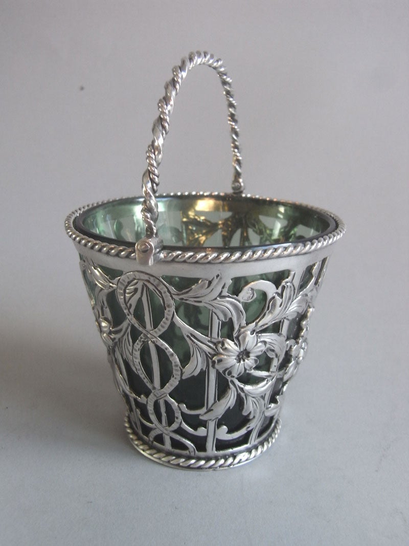 This rare example is modelled as a Milk Maids Pail and has a corded base, rim and arched handle. The sides are beautifully chased with foliate sprays and flower heads as well as vertical pails and entwined bands. The front of the Pail also displays