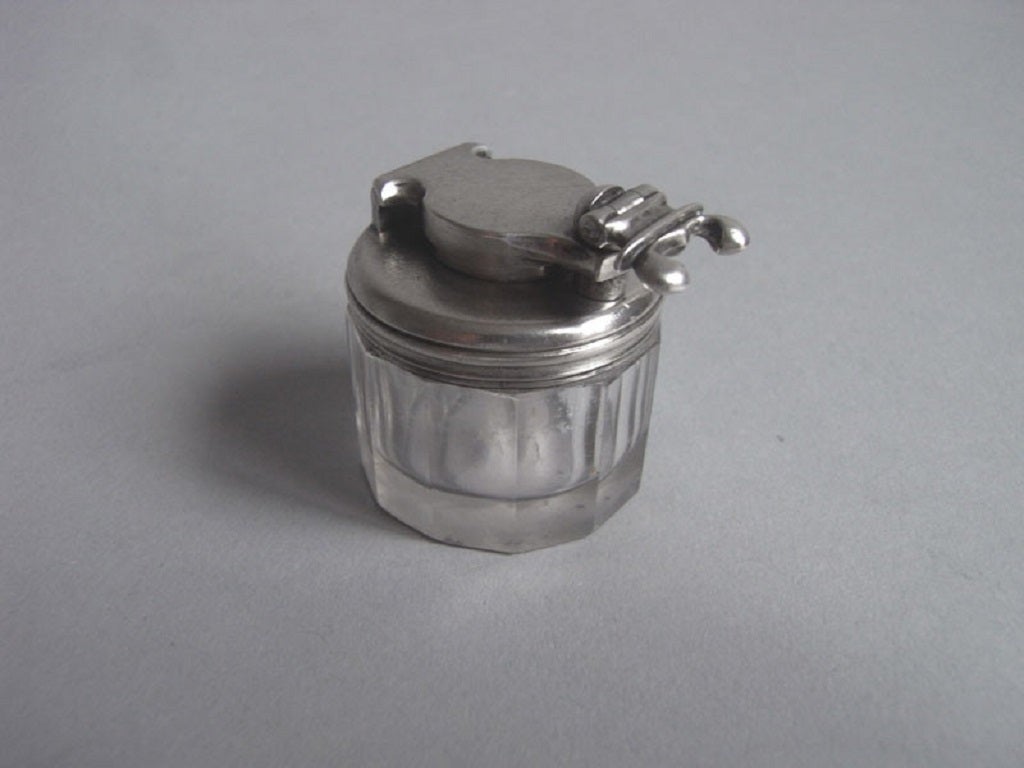 The Inkwell has reeded silver mounts and an unscrewable hinged cover. The glass inkwell has faceted sides. 

Height: 1.45 inches, 3.63cm 
Diameter: 1.1 inches, 2.75cm.