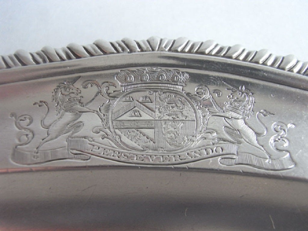 The Dish is oval in form with an unusual shaped raised rim decorated with gadrooning. The border is engraved, on one side, with a contemporary Armorial, flanked by supporters, with a Coronet above and Motto below. The other side is engraved with a