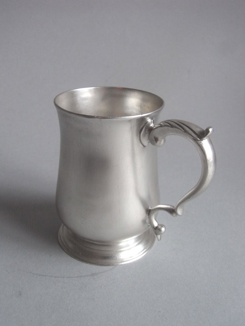 The Mug is of an unusual small size and was most probably made for a child. This piece stands on an applied circular foot decorated with reeding. The plain baluster main body rises to a slightly everted rim and the scroll handle is decorated with