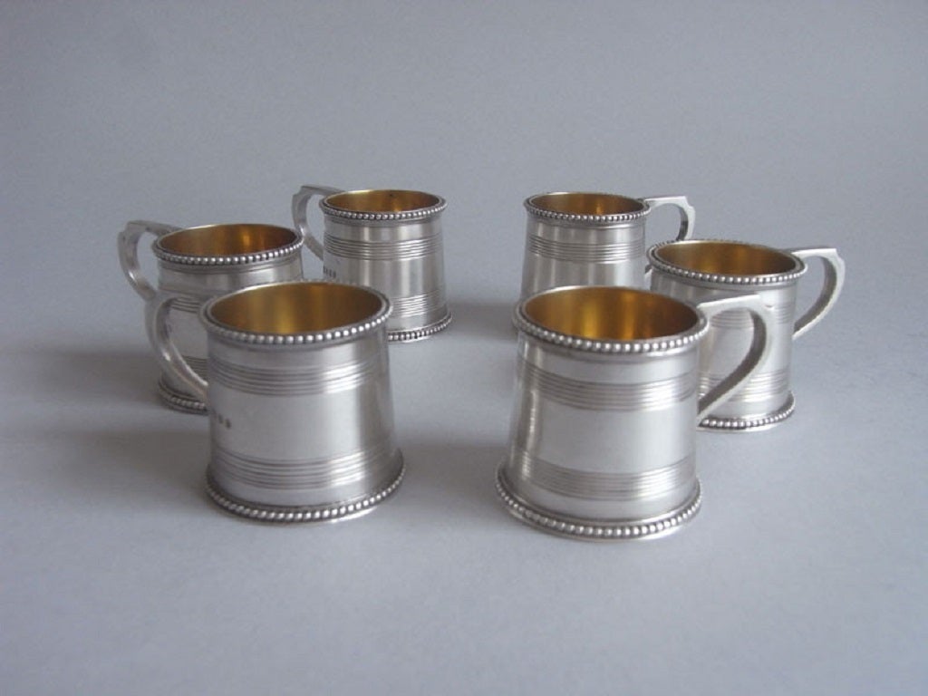 The mugs are modelled in the Georgian style and have tapering sides and a beaded rim and base. The sides are also decorated with reeding and each has a plain harp shaped handle. The interior displays original gilding and each has a crisp set of