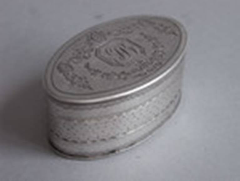 The Nutmeg Grater is oval in form and is engraved, on the cover, with Neo Classical floral garlands and roundels around a cut cornered cartouche, containing contemporary script initials. The sides are engraved with an eclectic mix of bright cut and