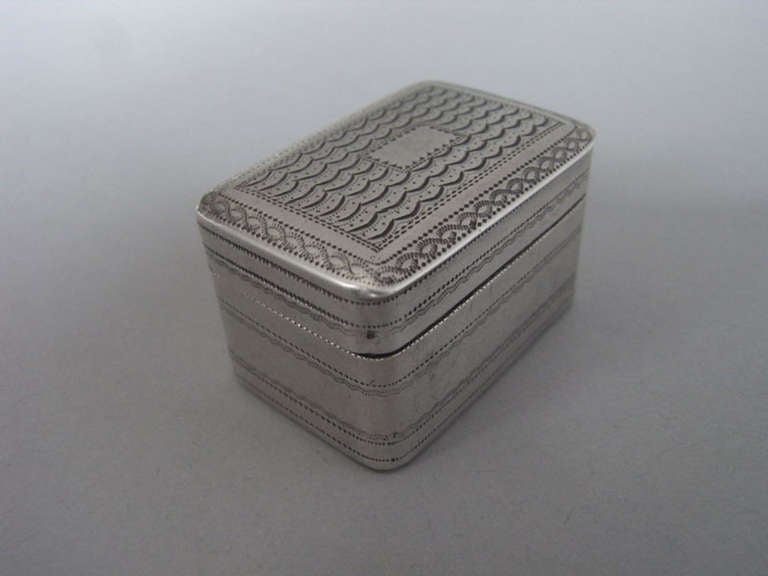 The Nutmeg Grater is broad rectangular in form with scale work designs on the cover around a vacant cartouche. The sides are decorated with prick dot bands and the base similarly, in addition to a central floral spray.