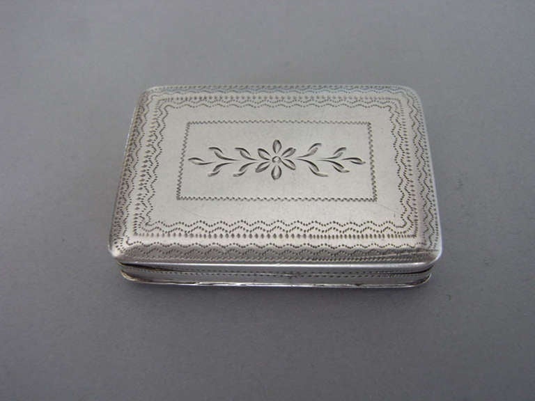 The Vinaigrette is slender broad rectangular in form. The cover is engraved with unusual horizontal bands of ovals and wriggle work, all surrounding an oval cartouche engraved with contemporary script initials. The base is engraved with prick dot