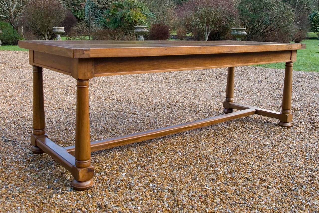 A late 19th century French farmhouse table in walnut, the chunky top above frieze with drawers at each end raised on turned legs united by an H stretcher and terminating in bun feet.