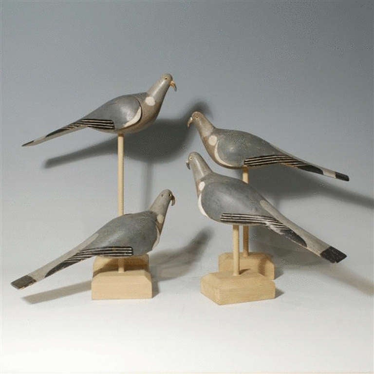 Four carved and painted wood pigeon decoys with glass eyes.