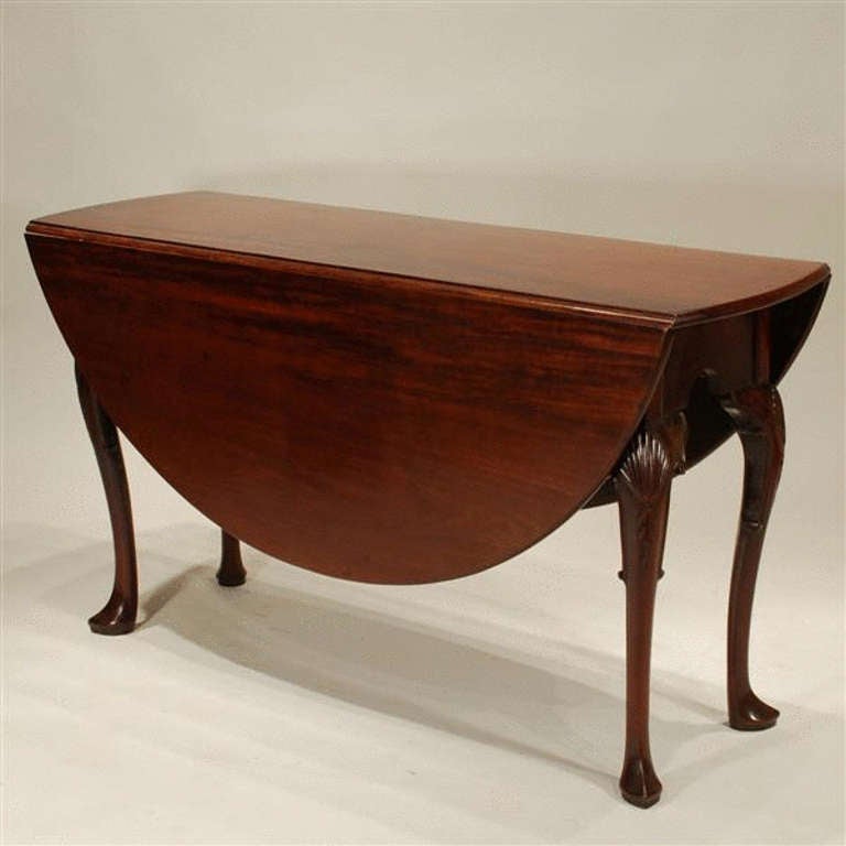 George I walnut drop leaf table of good colour. The near circular top supported on cabriole legs with carved shells to the knees, raised on pointed pad feet.