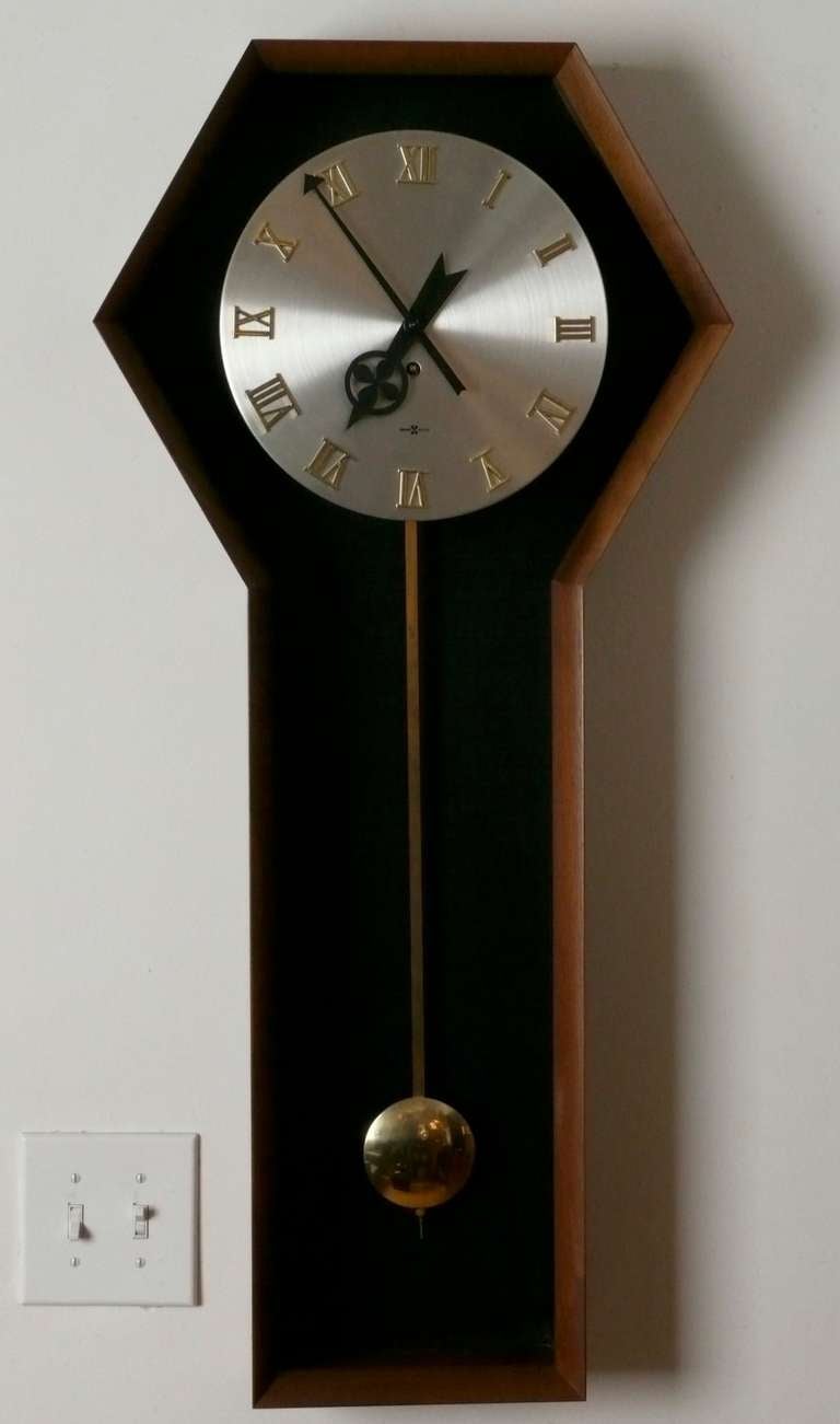 Beautiful oiled walnut case with brushed metal face, gold Roman numerals and brass pendulum c. 1962.  This model #557 wall clock was designed by George Nelson for Howard Miller and is in beautiful working condition, it has an 8 day wind and includes